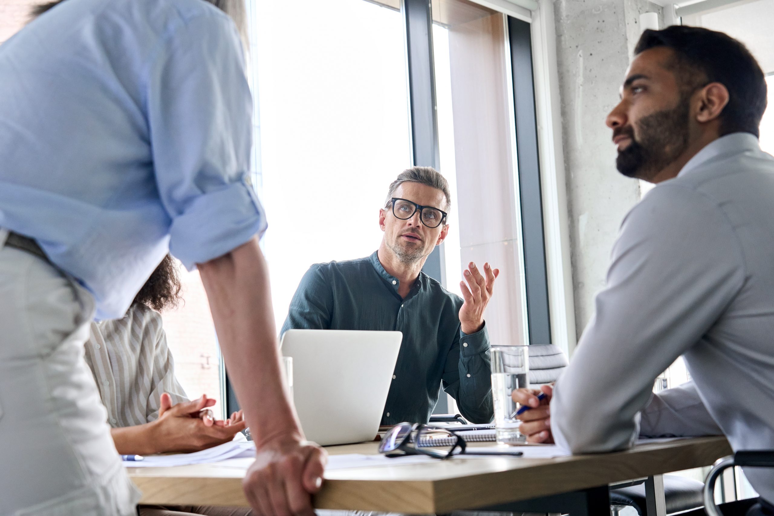 Diverse business people executive team brainstorming sharing ideas with female leader manager at board meeting working in teamwork discussing company strategy plan during corporate training.